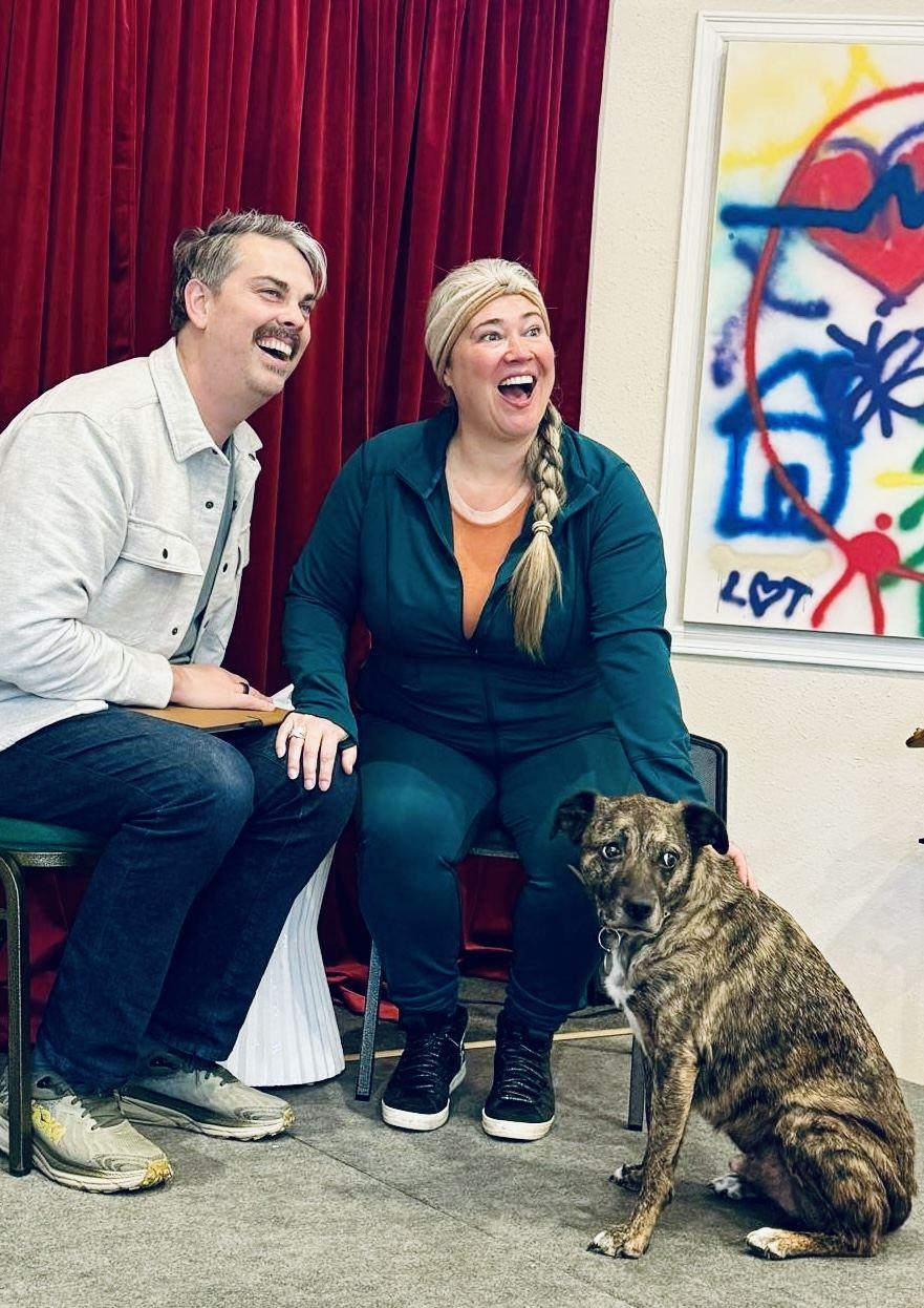 Geoff and Kathryn laughing together in the studio with their dog