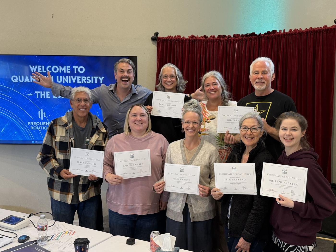 A graduating class holding their Quantum Biofeedback University certificates